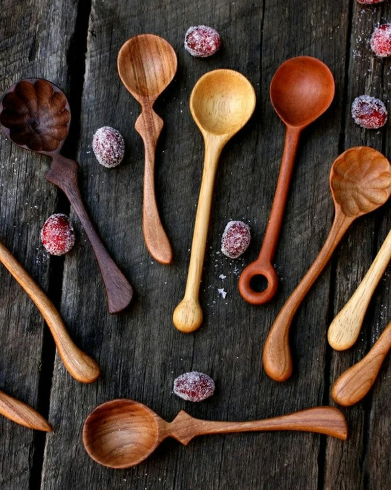 Wooden spoons of various sizes and colors on a dark wooden surface with dried berries.
